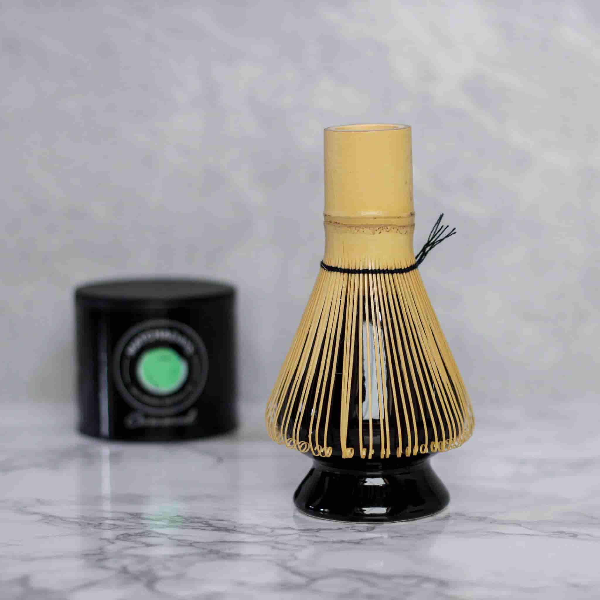 Accessoire, naoshi, support matcha pour fouet en bambou avec le fouet posé dessus et une boîte de matcha ceremonial dans le fond