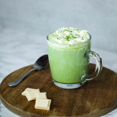 Grande tasse de matcha latte au chocolat bland avec sa creme chantilly