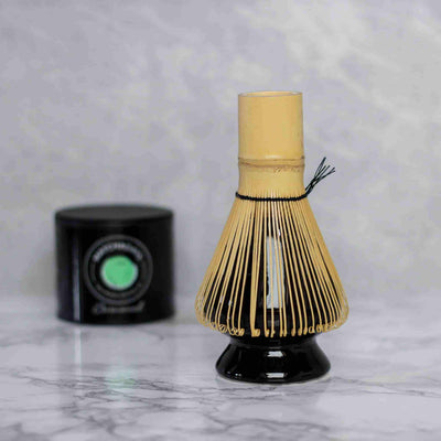 Accessoire, naoshi, support matcha pour fouet en bambou avec le fouet posé dessus et une boîte de matcha ceremonial dans le fond